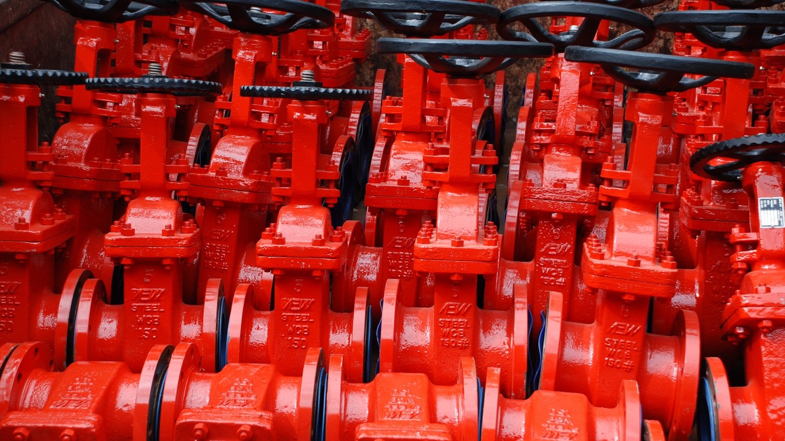 Rows of red flanged gate valves stored on an industrial rack.